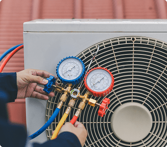 Hands adjusting air conditioning pressure gauges.