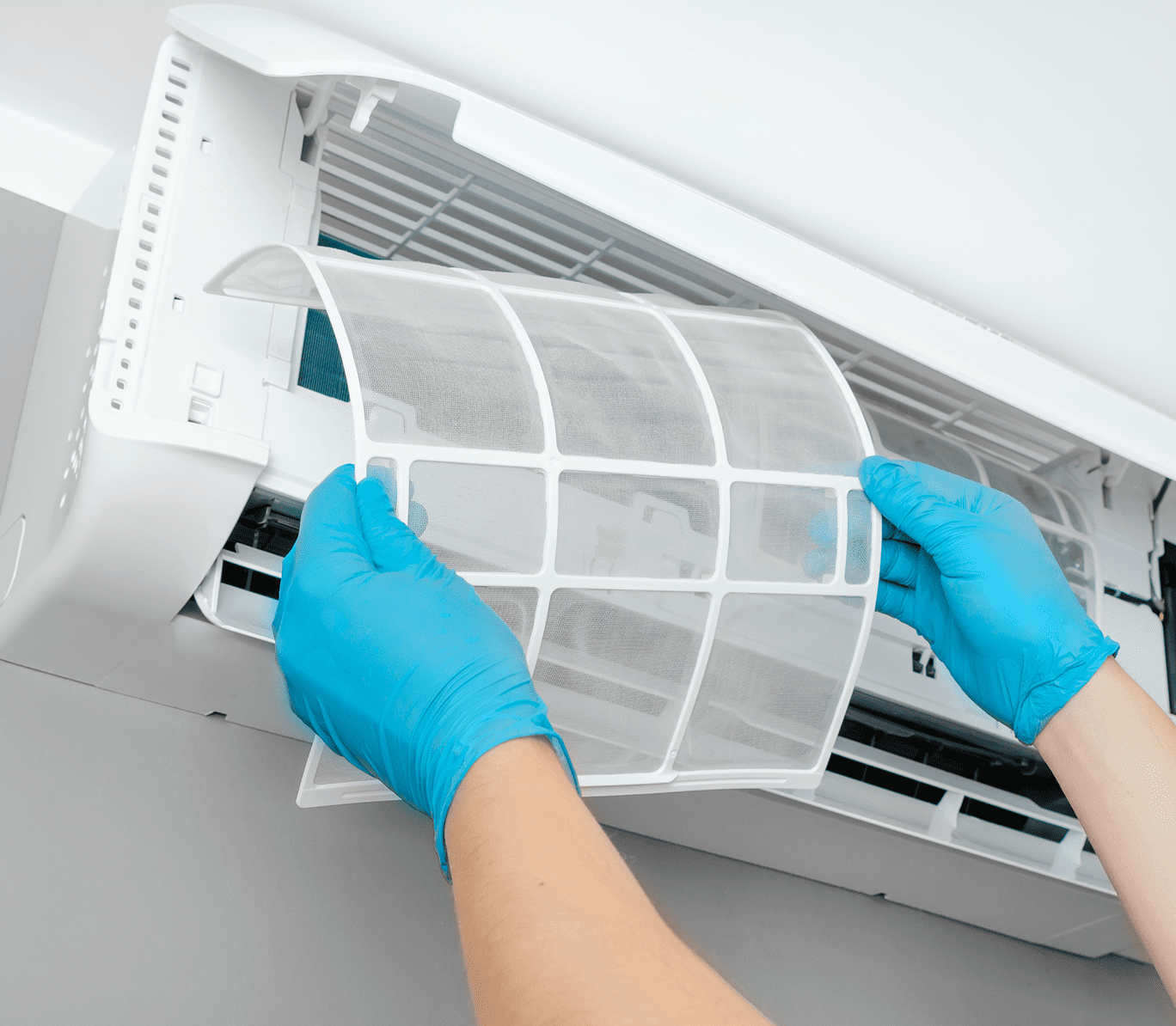 Cleaning air conditioner filter with blue gloves.